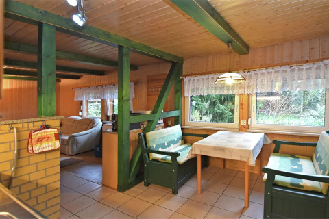 Gezellige lodge 'Neustadt' in Duitsland met groene balken, eettafel en bankjes bij het raam.
