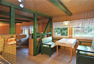 Gezellige lodge 'Neustadt' in Duitsland met groene balken, eettafel en bankjes bij het raam.