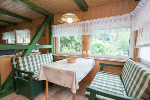 Gezellige eethoek in lodges Neustadt in Duitsland met geruite banken en uitzicht op de tuin.