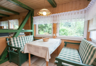 Gezellige eethoek in lodges Neustadt in Duitsland met geruite banken en uitzicht op de tuin.