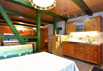 Wood-paneled kitchen and dining area with green beams in a cozy lodge in Neustadt, Germany.