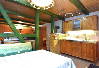 Houten keuken en eetgedeelte met groene balken in een gezellige lodge in Neustadt, Duitsland.