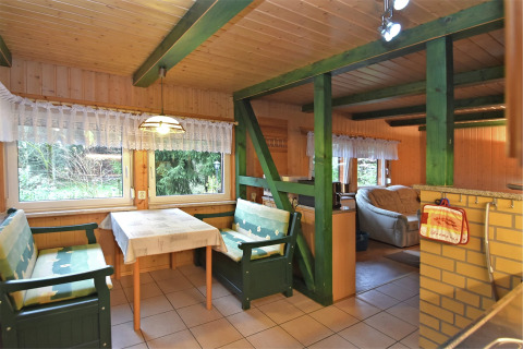 Eethoek in de lodge 'Neustadt' in Duitsland, met groene banken, kanten gordijnen en houten interieur.