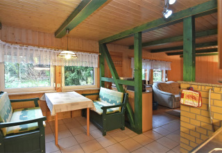 Eethoek in de lodge 'Neustadt' in Duitsland, met groene banken, kanten gordijnen en houten interieur.