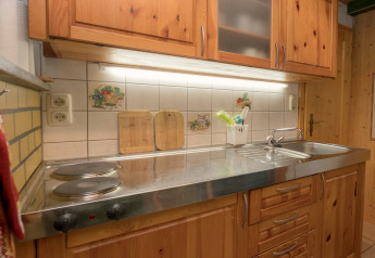 Cozy kitchen at Lodge Neustadt in Germany, featuring wooden cabinets, stove, and a stainless sink.