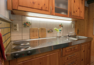 Gezellige keuken in lodge Neustadt in Duitsland met houten kasten, elektrische kookplaat en spoelbak.
