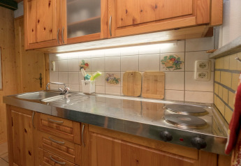 Cozy kitchen at Neustadt lodge in Germany featuring wooden cabinets, electric stove, and sink area.