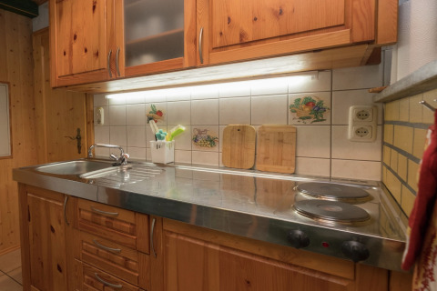 Gezellige keuken in lodge Neustadt in Duitsland met houten kasten, spoelbak en elektrische kookplaat.