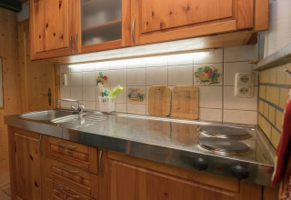Gezellige keuken in lodge Neustadt in Duitsland met houten kasten, spoelbak en elektrische kookplaat.