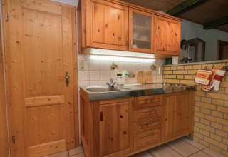 Gezellige keuken met houten kasten, spoelbak en kookplaat in lodge Neustadt in Duitsland.