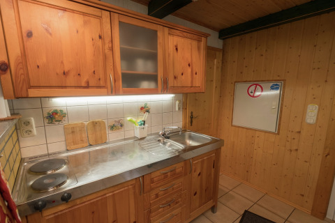 Kleine keuken met houten panelen in lodge Neustadt in Duitsland, met kookplaat en gootsteen.