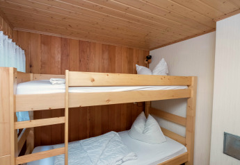 Room with wooden bunk bed, white bedding and wood paneling at Neustadt lodge in Germany.