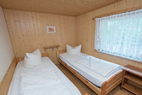 Slaapkamer met twee eenpersoonsbedden, houten wanden en groot raam in lodge Neustadt in Duitsland.