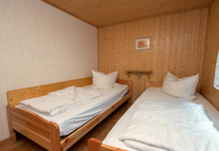 Zimmer mit zwei Einzelbetten, Holzvertäfelung und weißer Bettwäsche in der Lodge 'Neustadt', Deutschland.