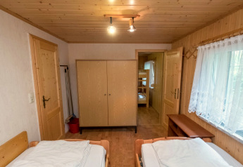 Cozy wooden room with two beds, wardrobe and bunks at Neustadt lodge in Germany, large window view.