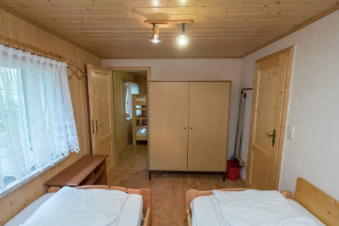 Gezellige houten slaapkamer in lodge Neustadt met twee bedden, kast en zicht op kamer met stapelbedden.