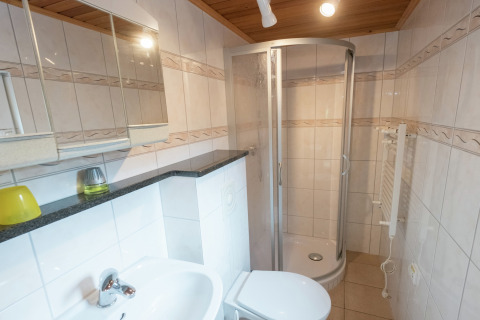 Moderne badkamer met douche, wastafel en toilet in lodge Neustadt, Duitsland, met betegelde muren.