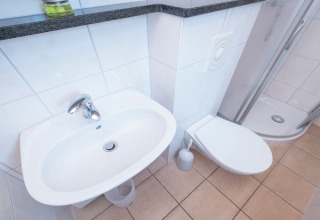 Modern badkamer bij lodge Neustadt in Duitsland met witte wastafel, toilet en douchecabine.