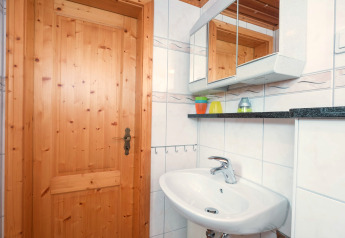 Bright bathroom at Neustadt lodge in Germany with wooden door, mirror cabinet, and white sink.