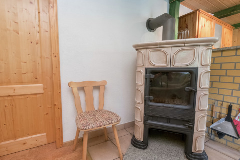 Gezellig hoekje in een lodge te Neustadt, Duitsland, met houten stoel en klassieke kachel.