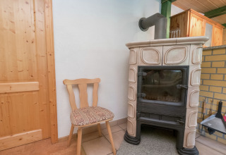 Gezellig hoekje in een lodge te Neustadt, Duitsland, met houten stoel en klassieke kachel.
