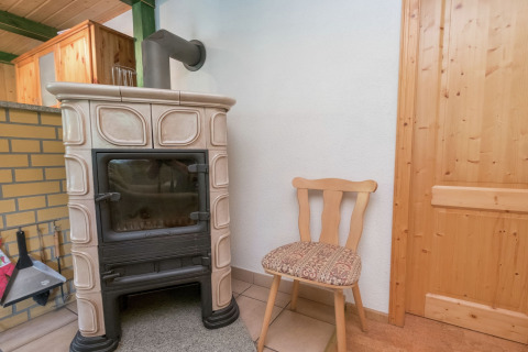 Houten stoel naast een klassieke houtkachel in een gezellige hoek van de lodge Neustadt in Duitsland.