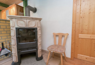 Houten stoel naast een klassieke houtkachel in een gezellige hoek van de lodge Neustadt in Duitsland.