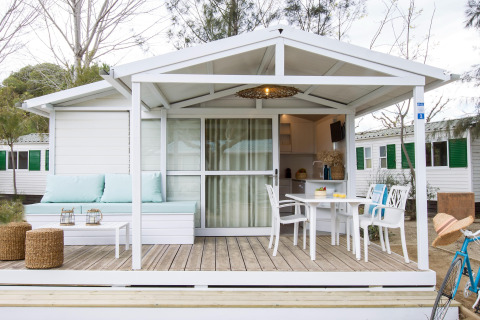 Wit chalet in Tamarit Park Resort met overdekte veranda, tuintafel, stoelen en comfortabele zithoek.