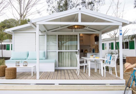 Wit chalet in Tamarit Park Resort met overdekte veranda, tuintafel, stoelen en comfortabele zithoek.