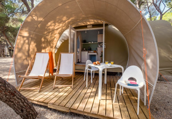 Terrasse extérieure à l'entrée d'une tente safari avec chaises, table et petit-déjeuner au Camping Estival Torre de la Mora, Espagne.