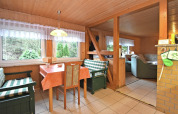 Eethoek met groene geruite banken, houten interieur en boszicht in een Duits vakantiechalet.