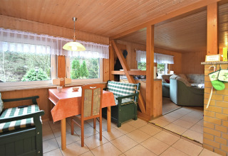 Zona pranzo con panche verdi a quadri e vista bosco, interno in legno in chalet tedesco.