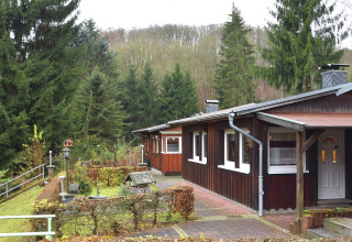 Træhytte ved Holiday home «with Parking» i Tyskland, omgivet af grantræer og en velplejet have.