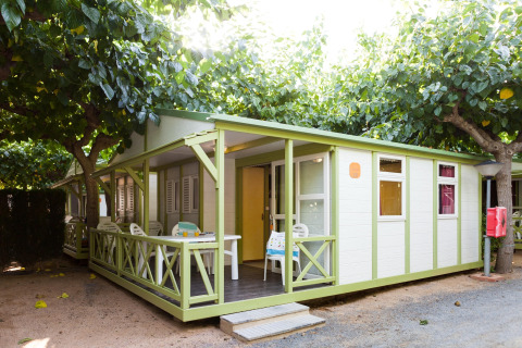 Buitenzicht van een Premium Bungalow bij Camping Cambrils Playa met terras en groene bomen.