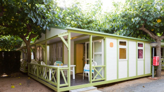 Vue extérieure d’un bungalow Premium au Camping Cambrils Playa, terrasse sous arbres verdoyants.