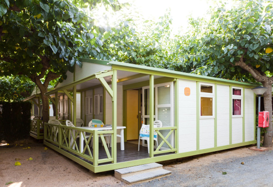 Buitenzicht van een Premium Bungalow bij Camping Cambrils Playa met terras en groene bomen.