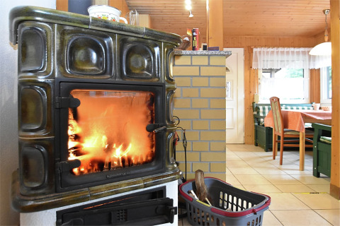 Knusse chalet woonkamer in Duitsland met houtkachel, zithoek en houten meubelen bij het raam.