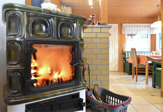 Gemütlicher Wohnbereich im Chalet in Deutschland mit Kaminofen, Essplatz und Holzmöbeln am Fenster.