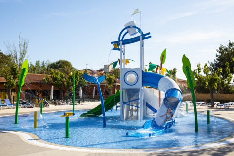 Parc aquatique pour enfants avec toboggans et jeux d'eau dans un hébergement glamping sous le soleil.