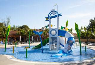 Parc aquatique pour enfants avec toboggans et jeux d'eau dans un hébergement glamping sous le soleil.