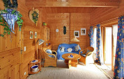 Gezellige houten chalet woonkamer met blauwe bank, rieten stoelen en bloemen gordijnen in Duitsland.