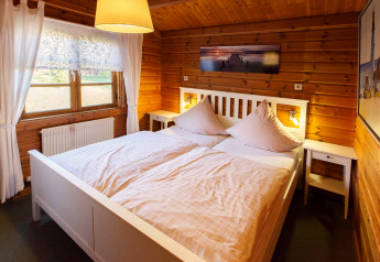 Chambre dans un chalet en bois au Holiday Park Lauterdörfle, lit double, fenêtre et tableau, Allemagne.
