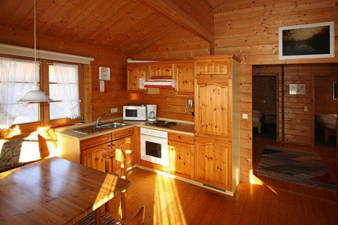 Cucina e zona pranzo rivestite in legno in uno chalet al Holiday park Lauterdörfle, Germania.