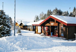 Cabañas de madera cubiertas de nieve en Holiday park Lauterdörfle, Alemania, paisaje invernal sereno.
