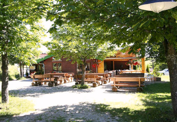 Outdoor seating with wooden benches at Holiday park Lauterdörfle chalet, shaded by trees in Germany.