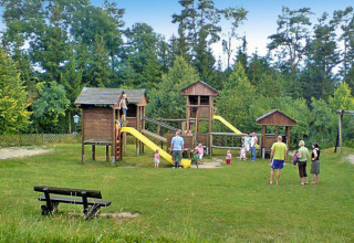 Kinderen en volwassenen spelen op een houten speeltuin aan Holiday park Lauterdörfle in Duitsland.