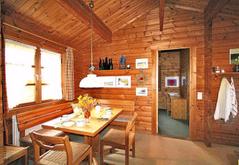 Foto van een knusse eetruimte in een houten chalet, met gedekte tafel en rustieke wanddecoraties.