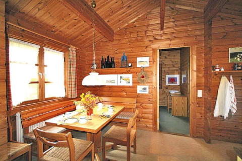 Photo d'un coin repas chaleureux dans un chalet en bois, table dressée et décorations rustiques.