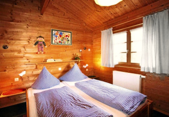 Cozy bedroom in a wooden chalet with two single beds, blue checkered bedding, and light curtains.