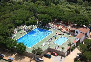 Luftfoto af glampingsted med to swimmingpools, solsenge og grønne omgivelser i en skov.